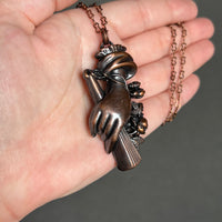 Hand Holding a Fan and a Rose Copper Necklace